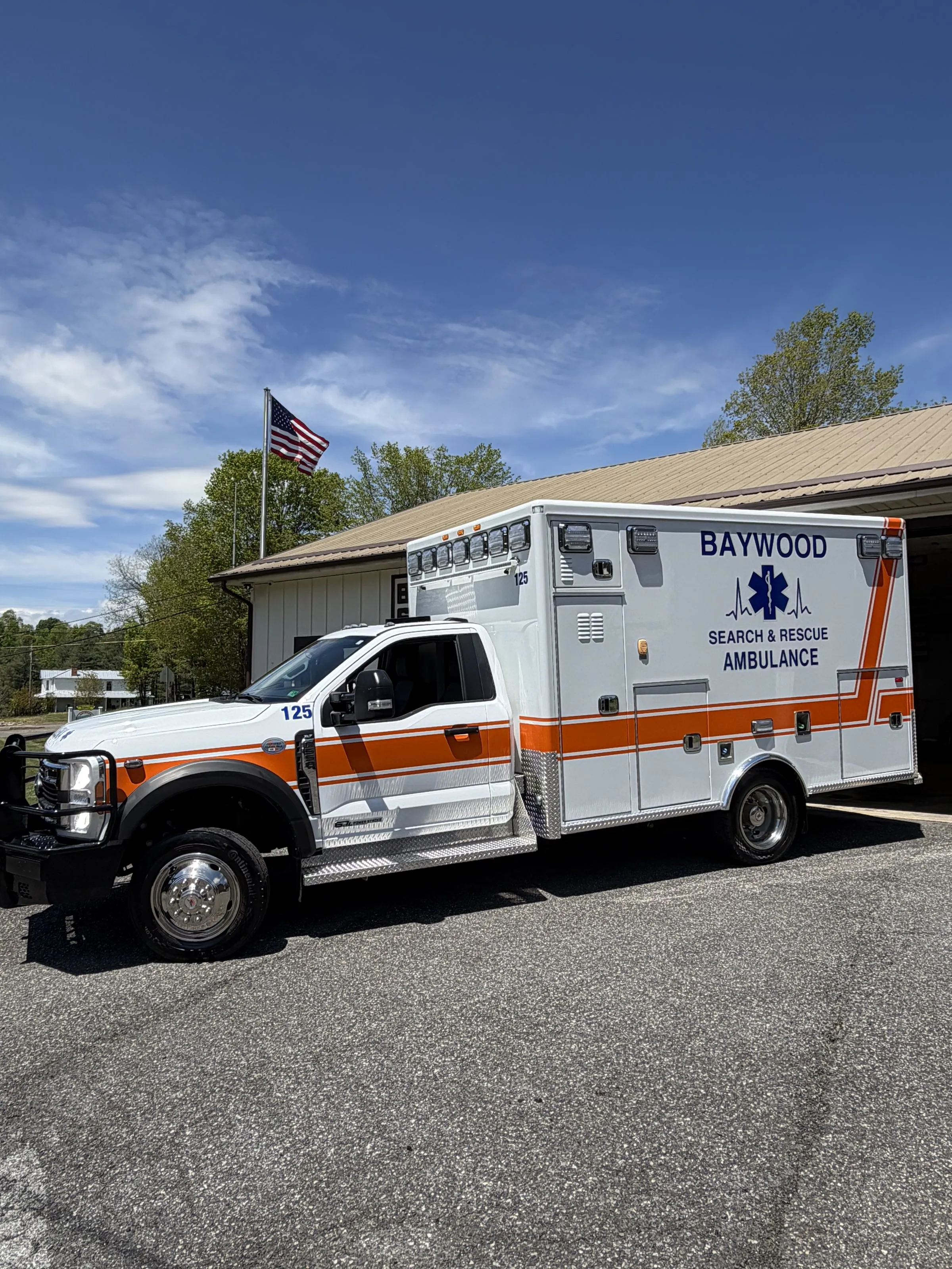 Baywood ALS ambulance parked at the station with the flag flying overhead